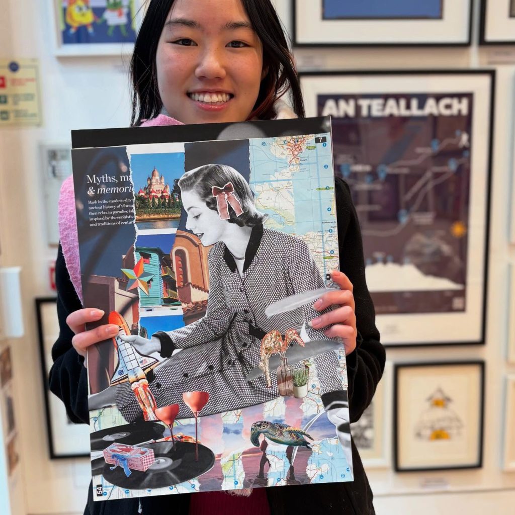 A young woman smiles, holding up a collage she has created as part of a CamCreatives workshop.